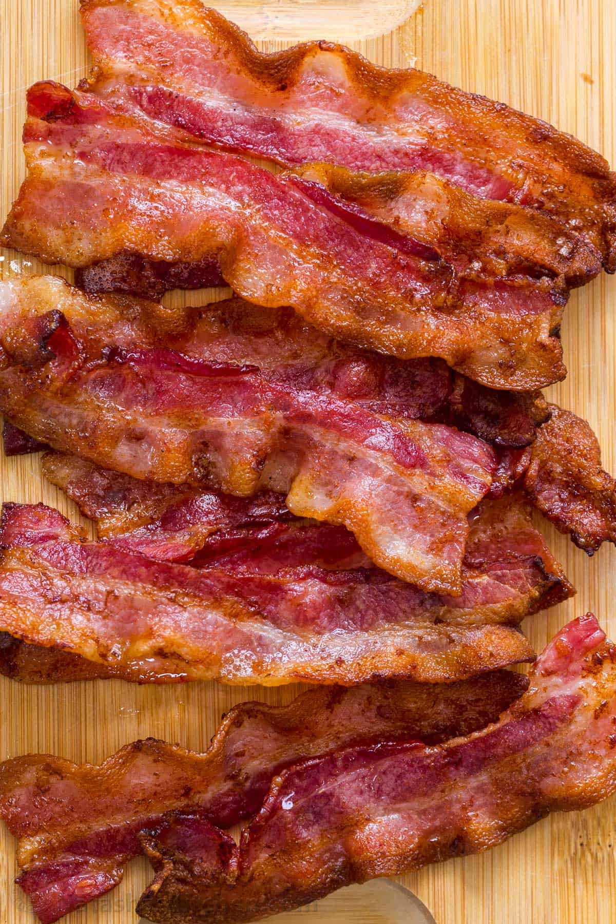 Crispy cooked bacon laid out on a cutting board. 