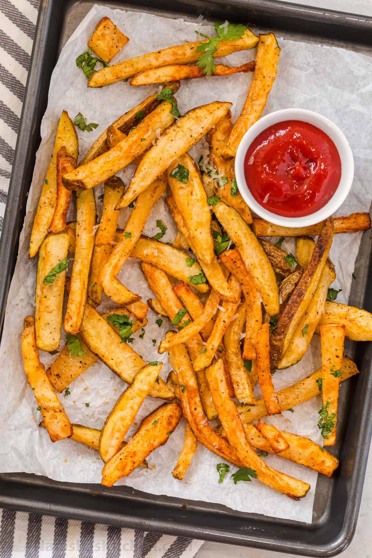 Sliced potatoes on parchment with ketchup