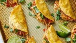 Baked Chicken Tacos on a cooking sheet with lime slices