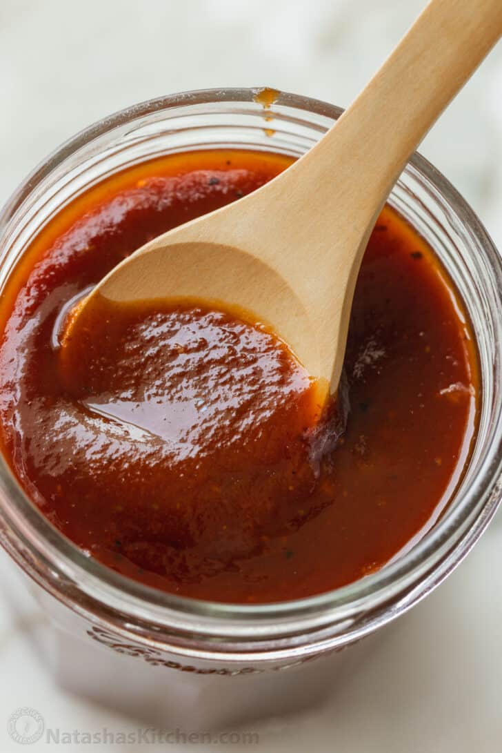 Jar of homemade BBQ sauce with wooden spoon