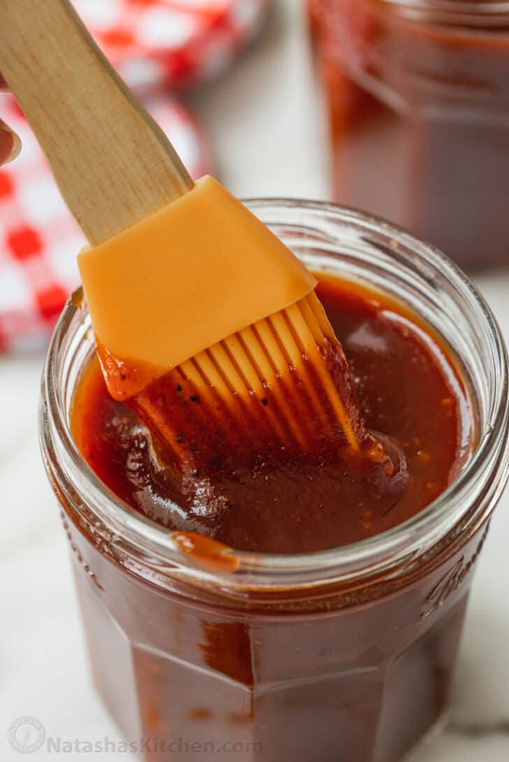 Silicone brush dipping into jar of homemade barbecue sauce