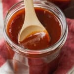 Closeup of barbecue sauce in jar with wooden spoon