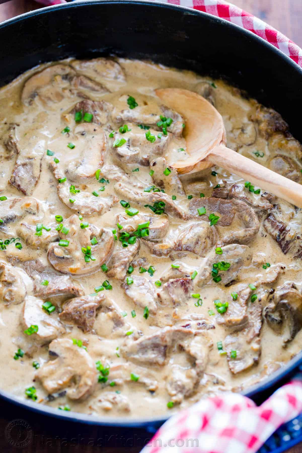 Beef stroganoff with serving spoon garnished with chives