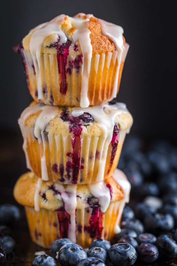 Blueberry Muffins glazed and stacked surrounded by fresh blueberries