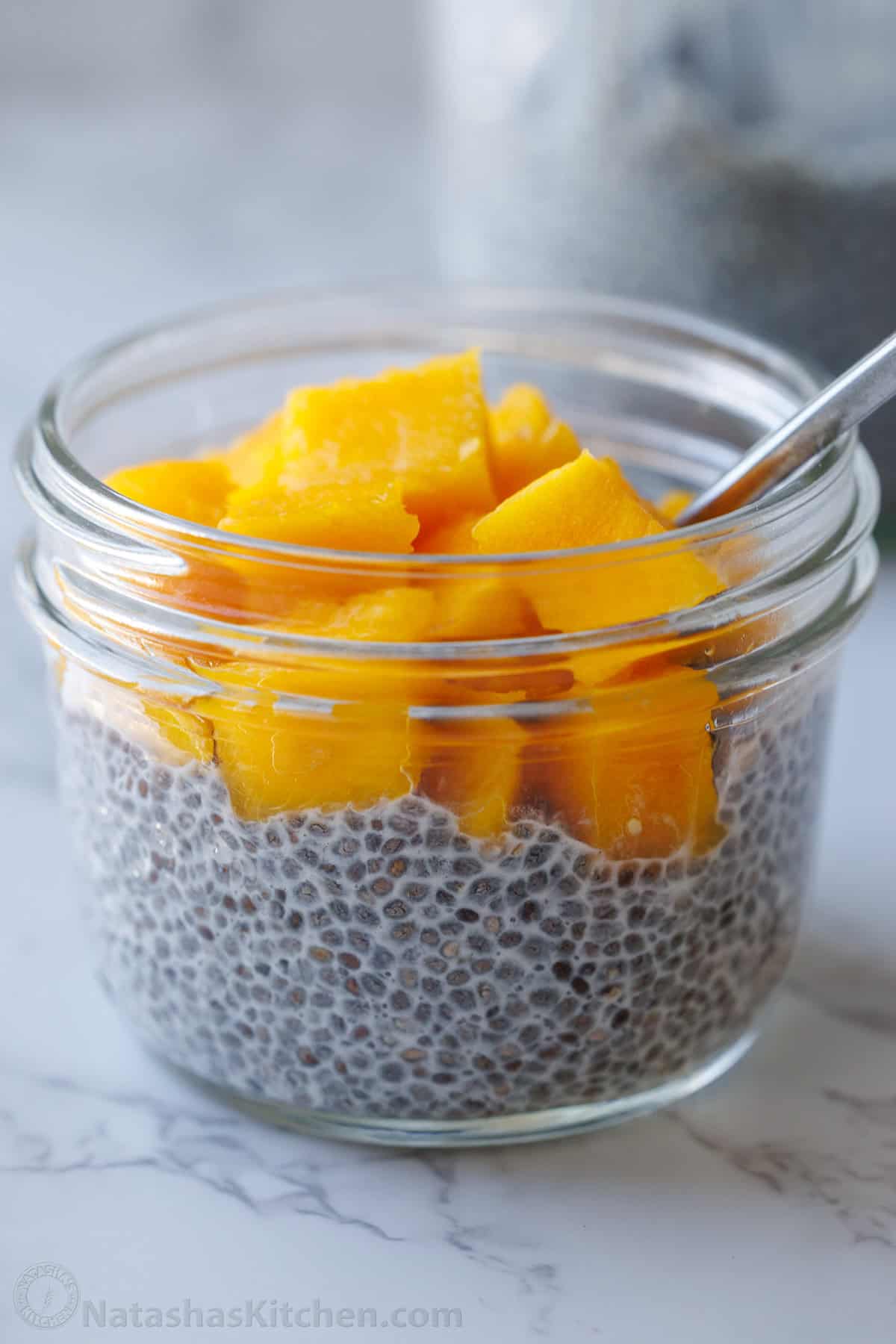 Mango chia pudding in a small jar with a spoon
