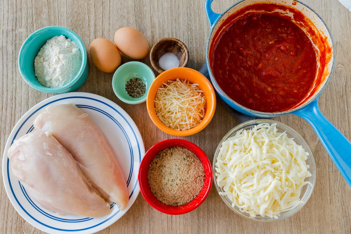 Ingredients for chicken parmesan with homemade marinara sauce, chicken breast, cheese, bread crumbs, eggs, flour and seasonings