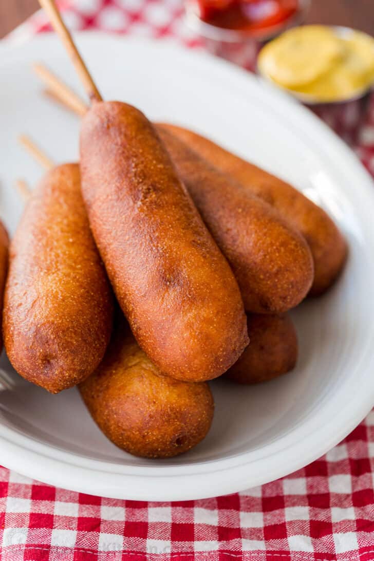 homemade corn dogs on a serving plate with ketchup and mustard