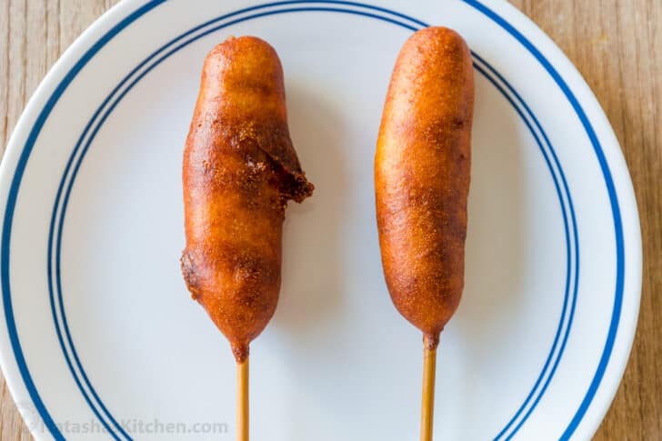 a cracked corn dog next to a perfect corn dog