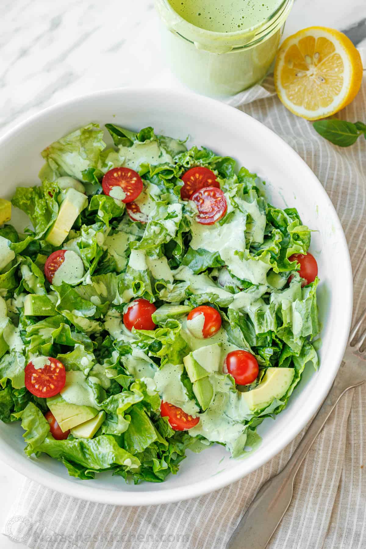 Fresh salad with tomatoes covered with Greek Goddess Dressing in a white bowl