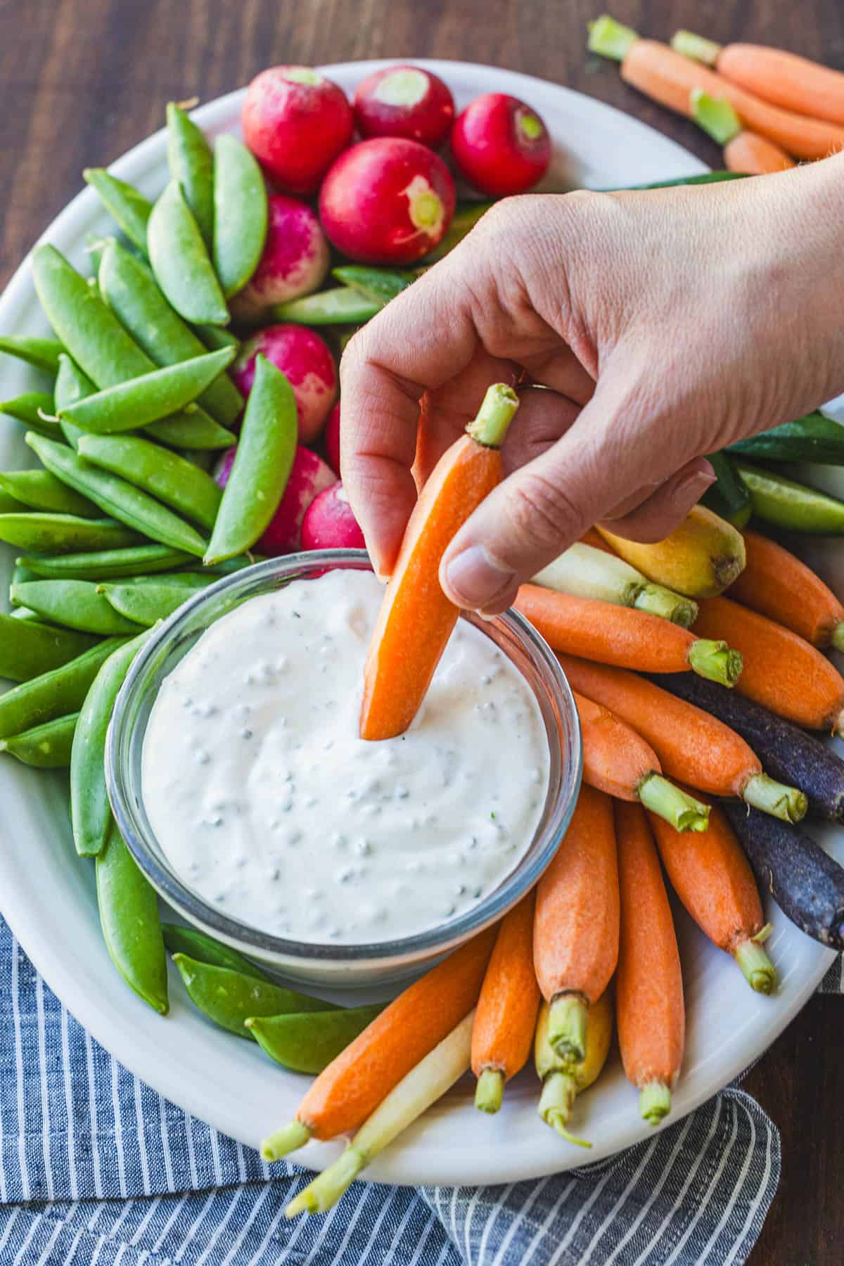 Dipping ray carrots into homemade Ranch Dip from a veggie tray