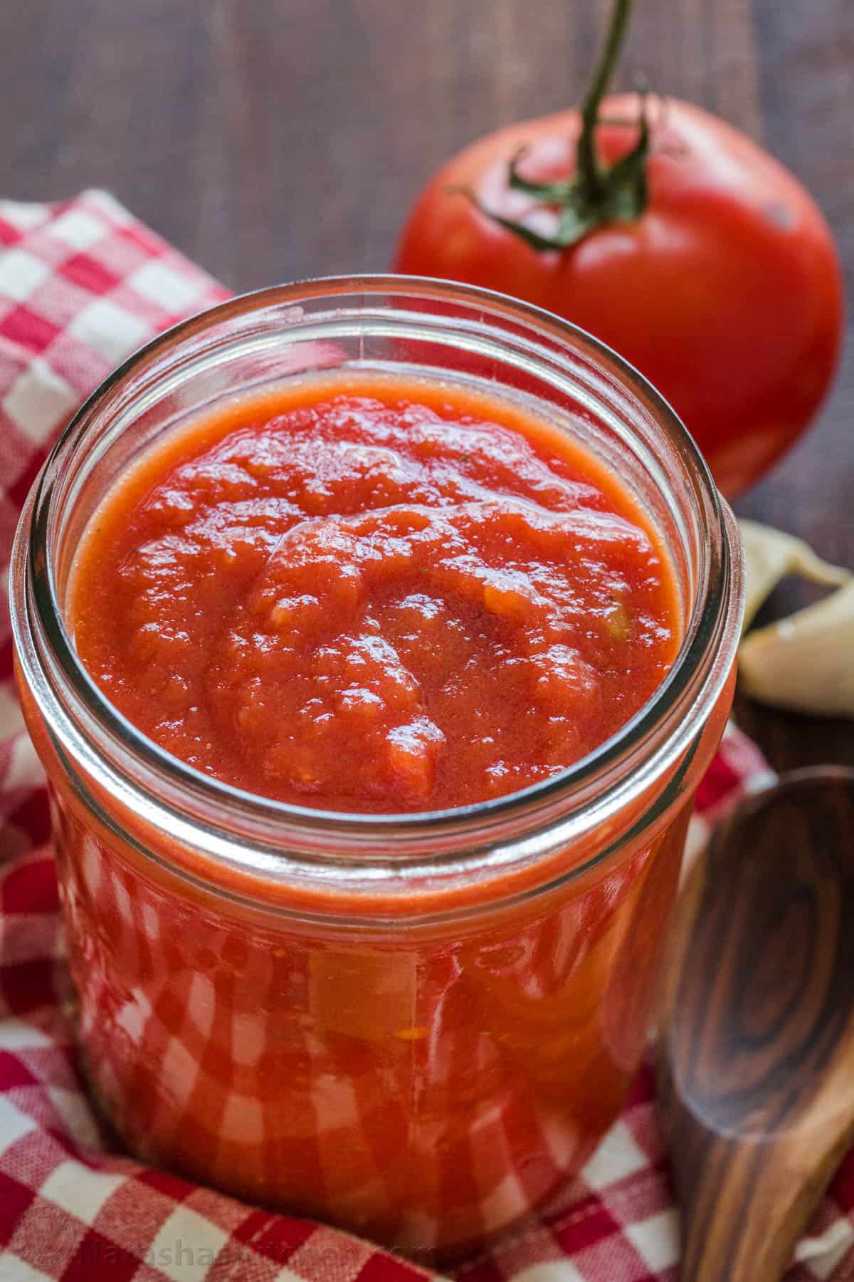 Homemade Red Sauce for Pizza in mason jar with tomatoes in the background