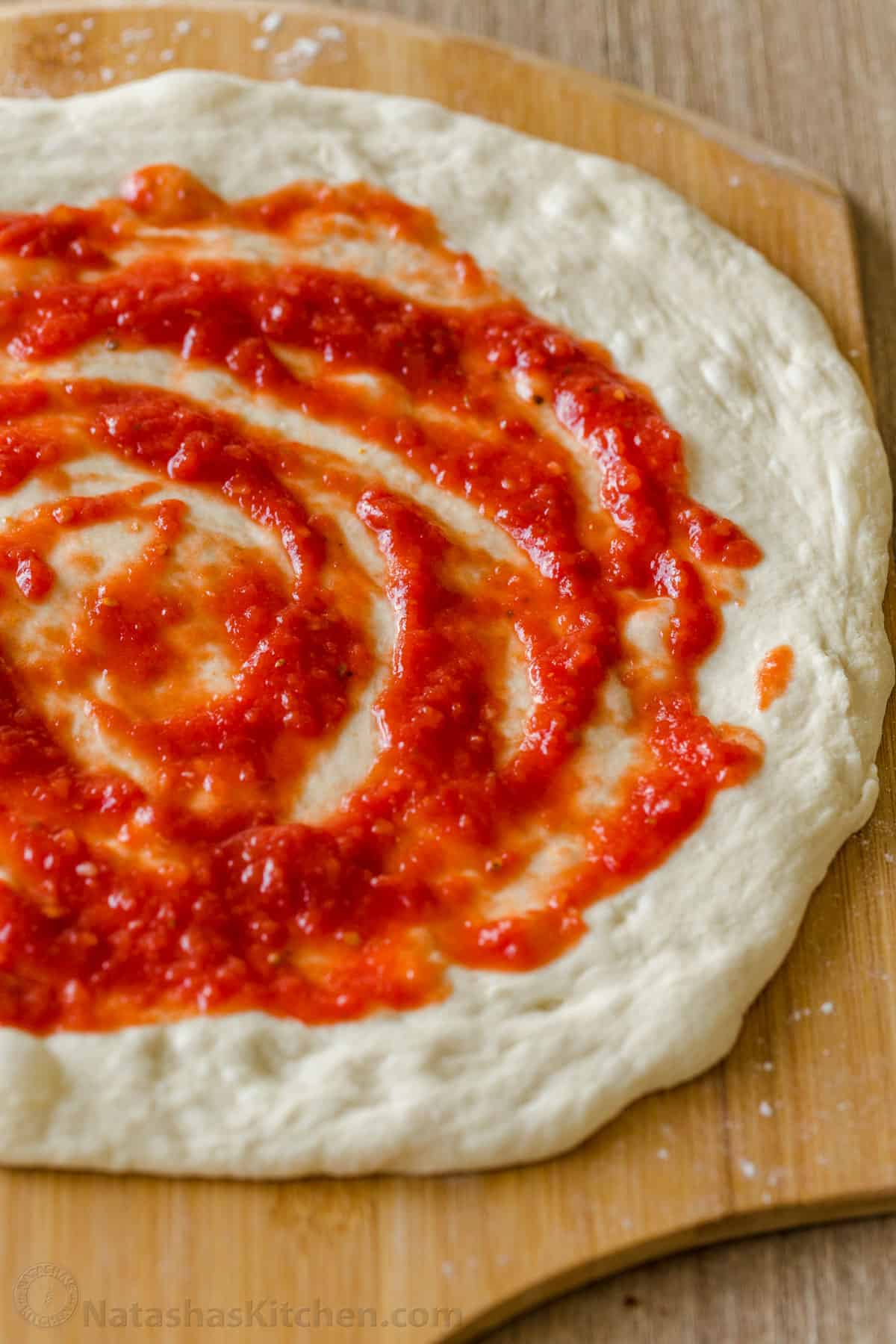 Homeamde Red Pizza Sauce swirled on pizza dough