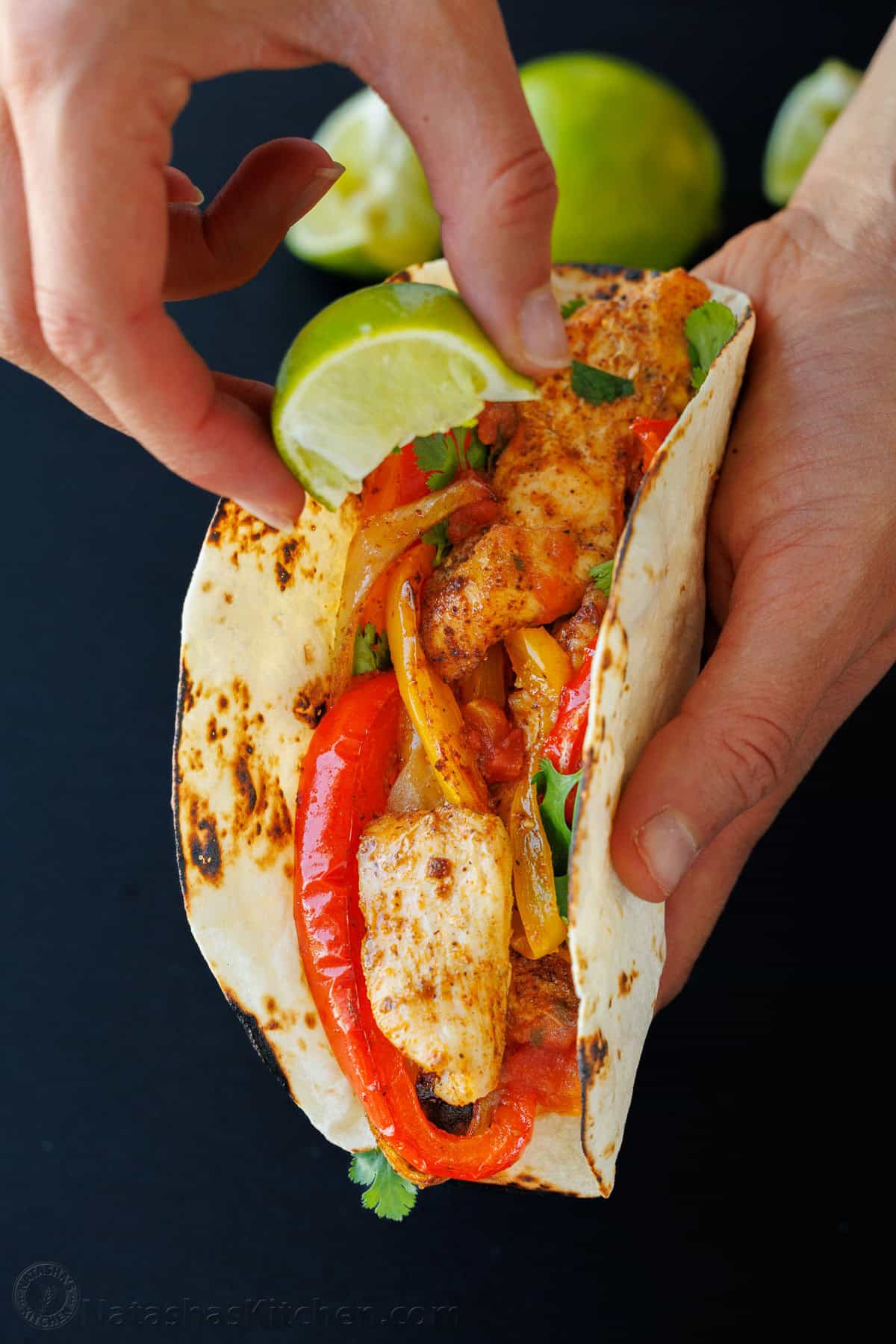 Drizzling lime on a fajita in a tortilla