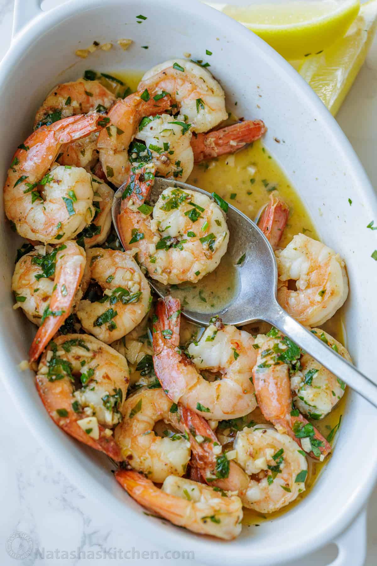 Shrimp scampi recipe in a white dish with butter garlic sauce and parsley garnish