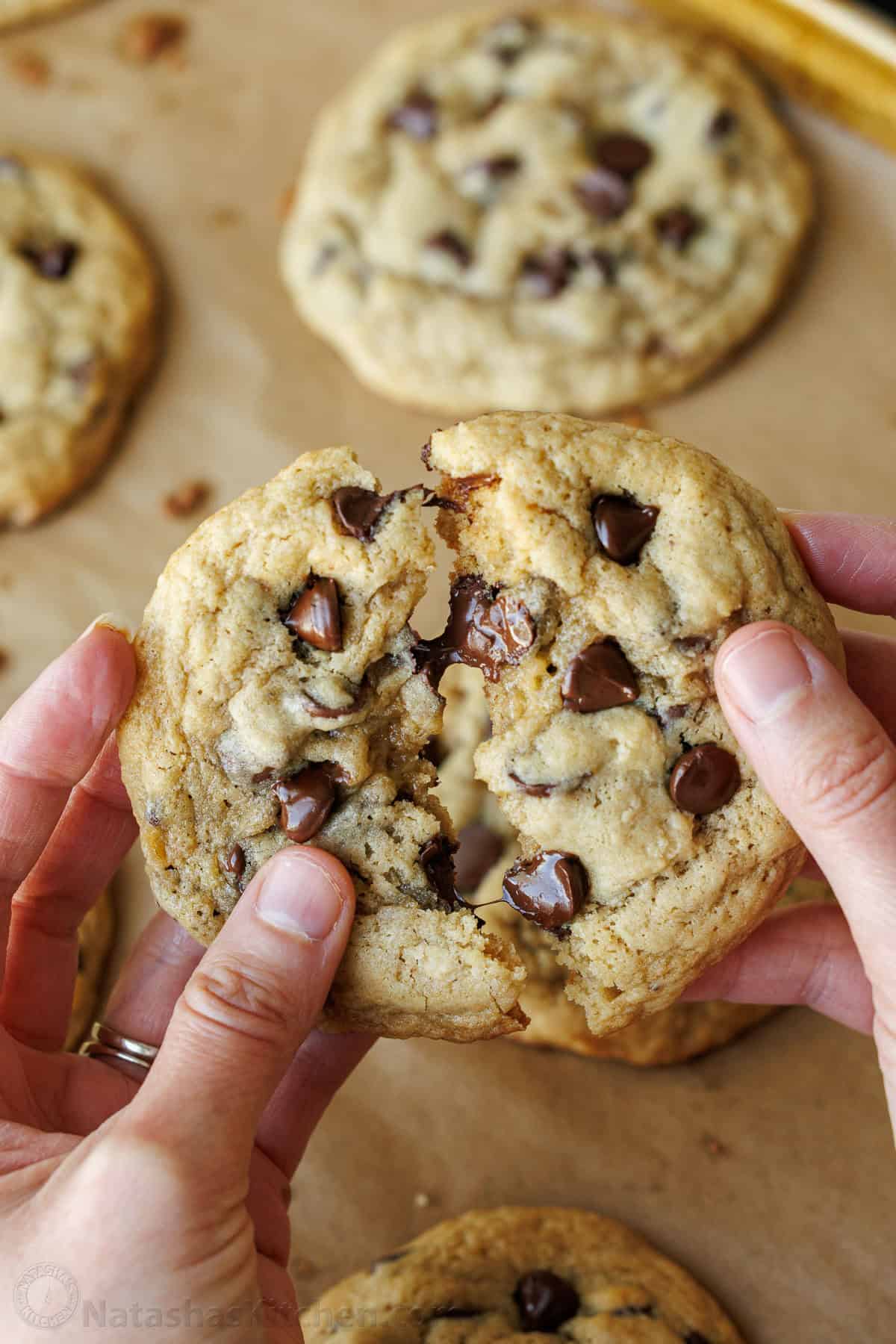 two hands pulling apart an easy sourdough chocolate chip cookie using discard