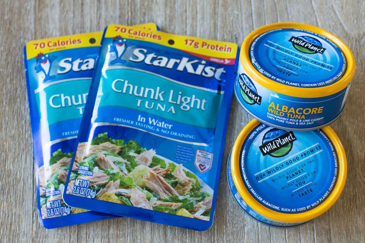 Two packets of StarKist chunk light in water next to two cans of Wild Planet canned fish.